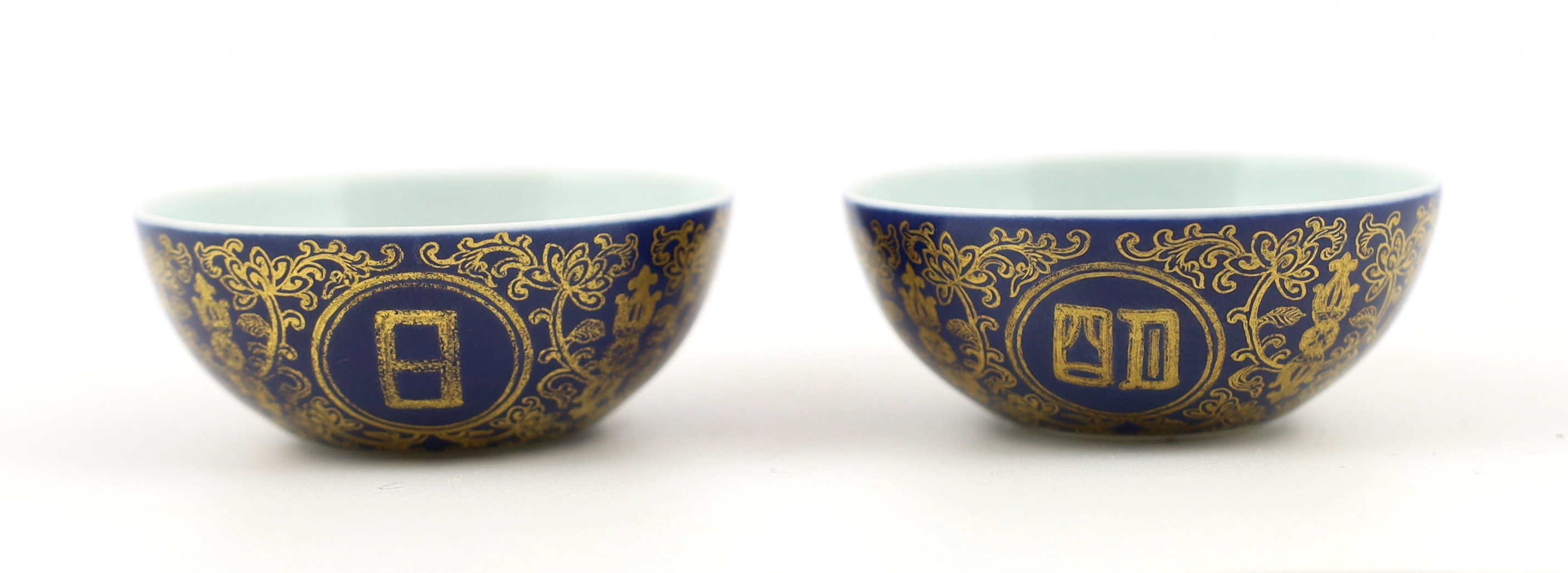 A pair of Chinese gilt decorated blue ground cups, Qianlong mark but later, one cracked